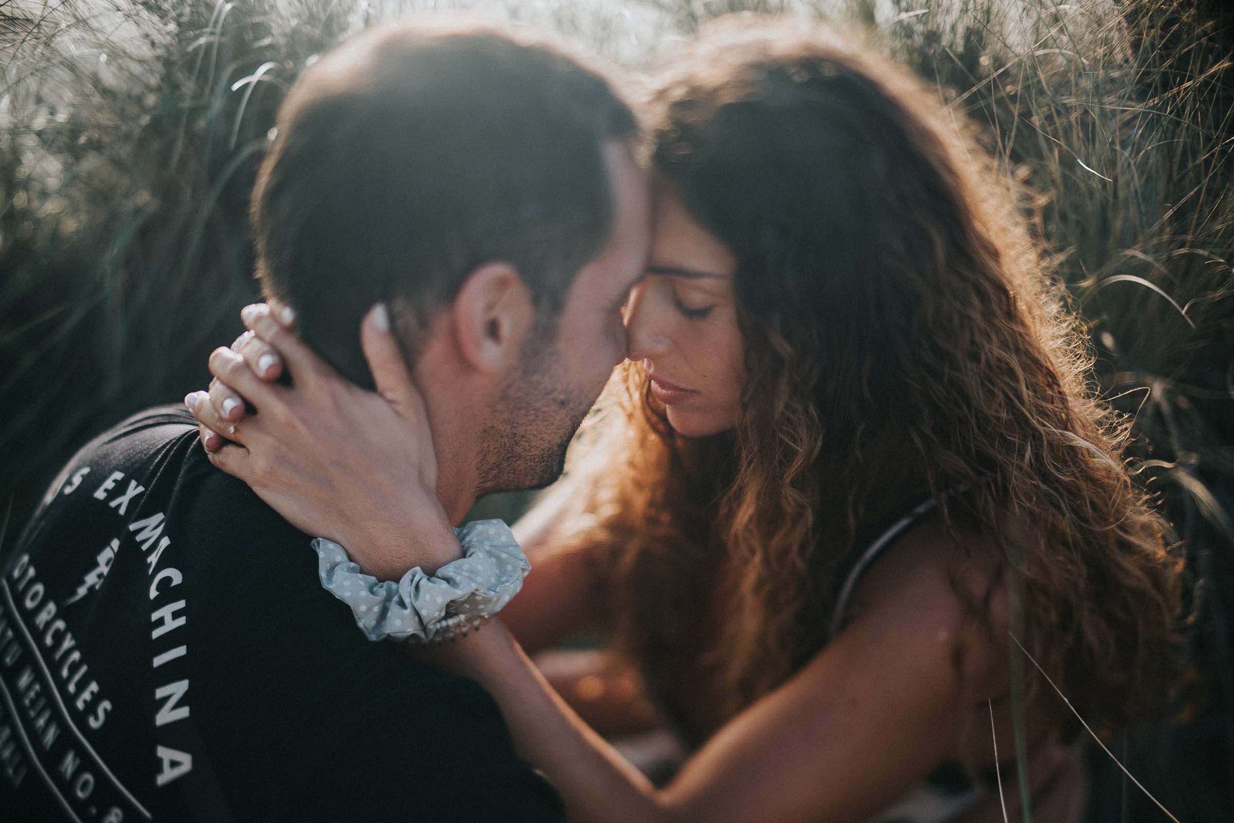 couple sitting in the grass touching foreheads