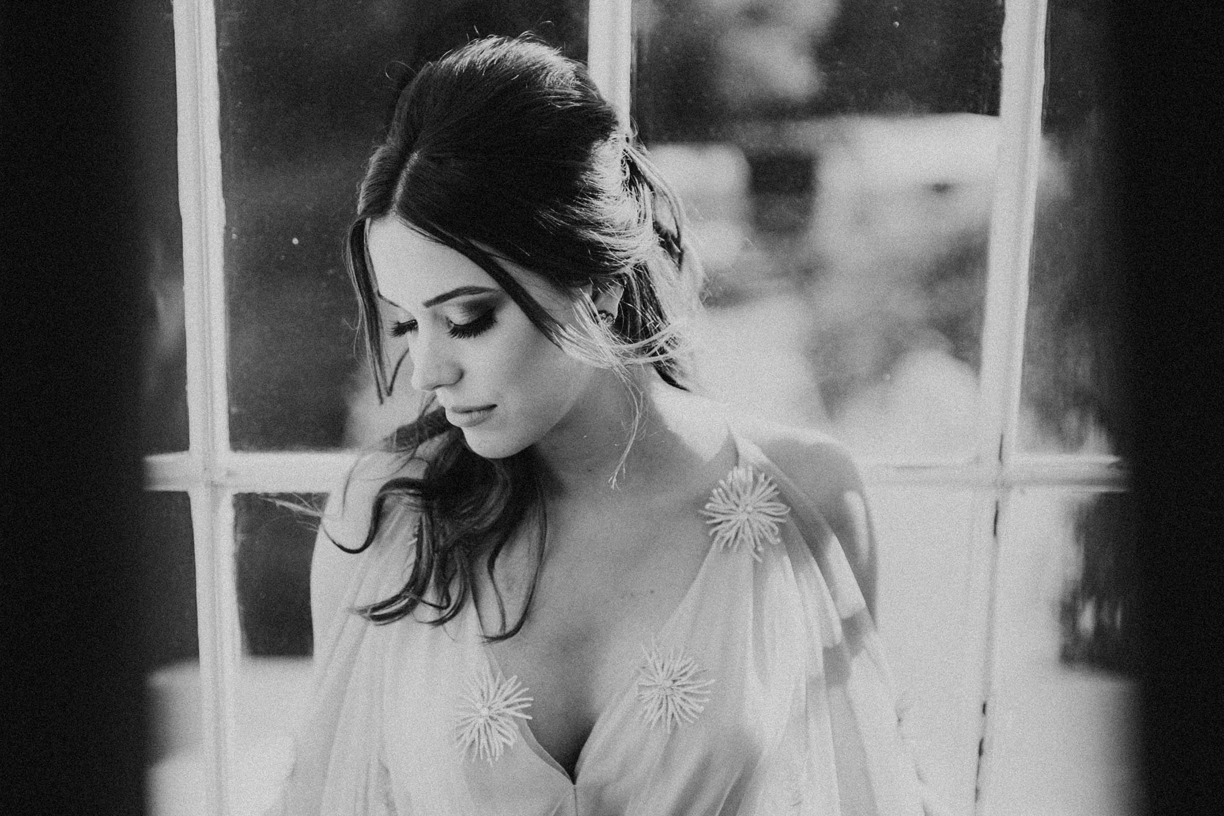 black and white photo of a bride next to a window