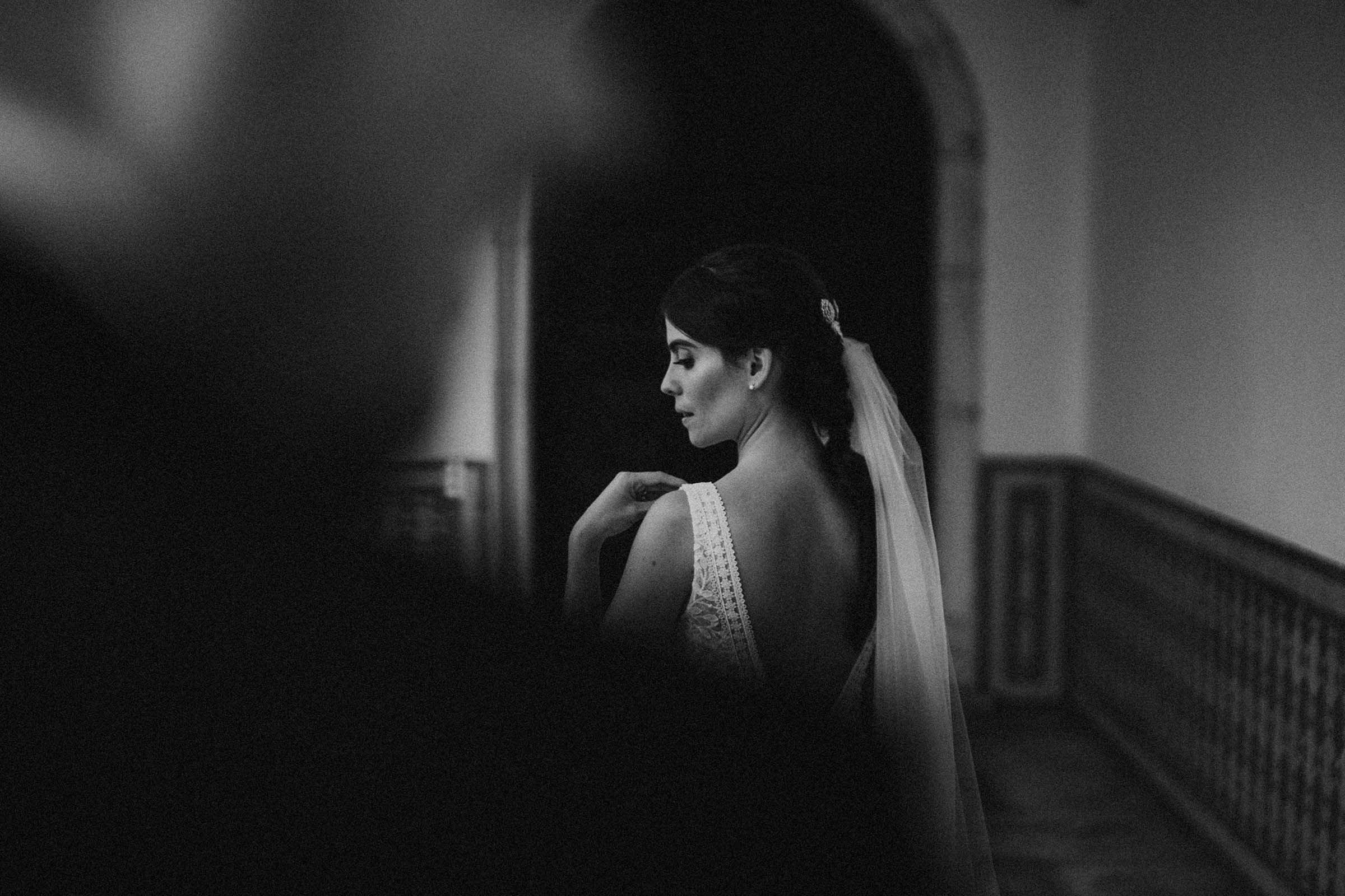black and white photo bride touching her shoulder with groom in foreground out of focus